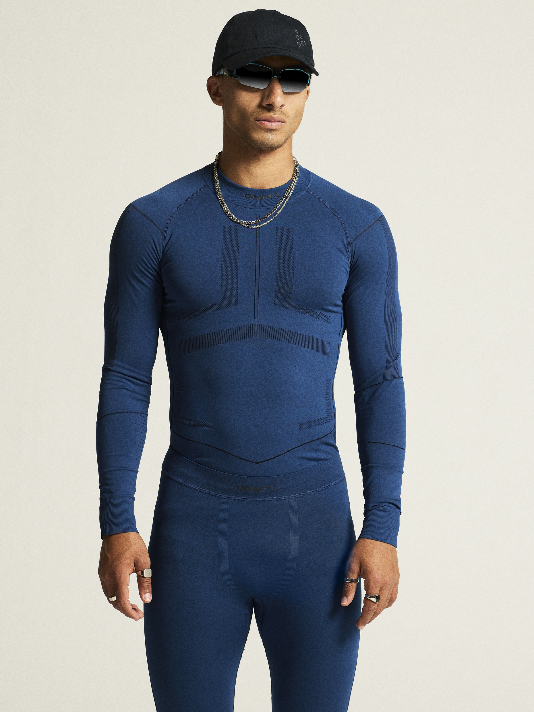Man models a blue Craft Sportswear base layer top and bottoms for athletic wear.