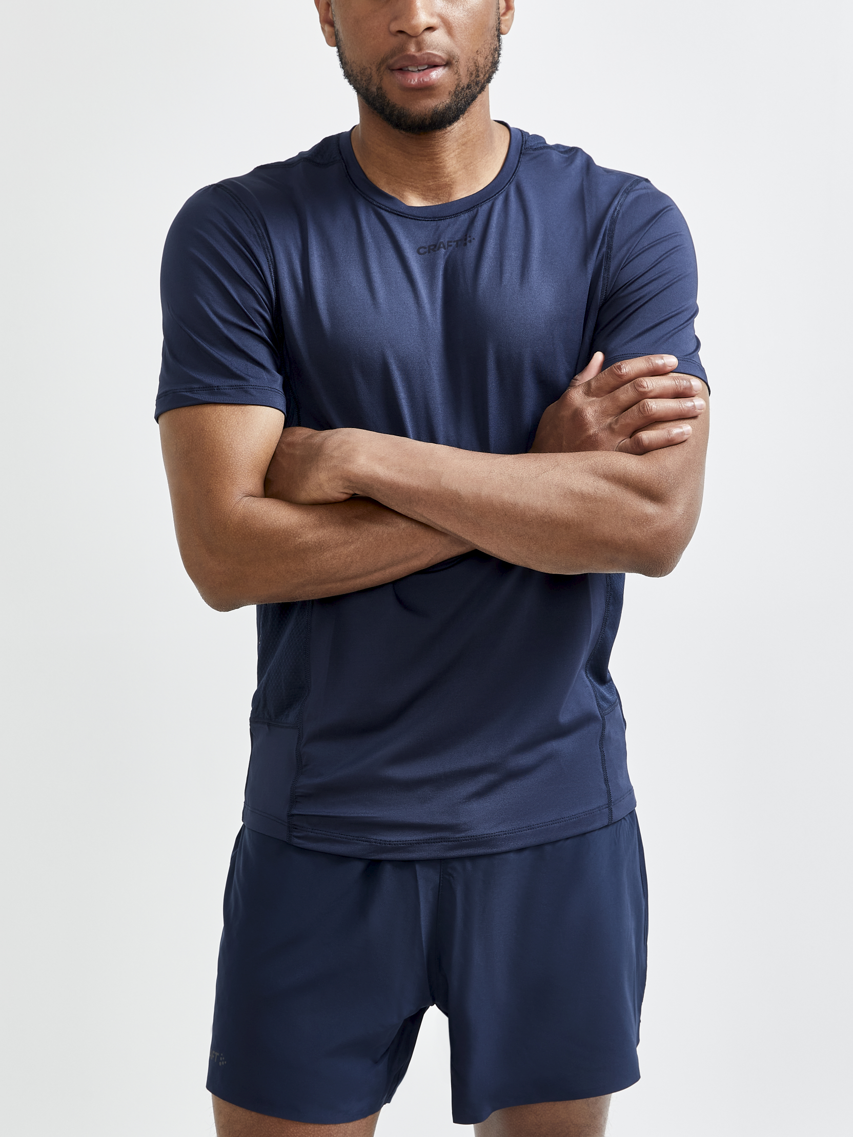 Man models a navy blue Craft Sportswear athletic t-shirt and running shorts.