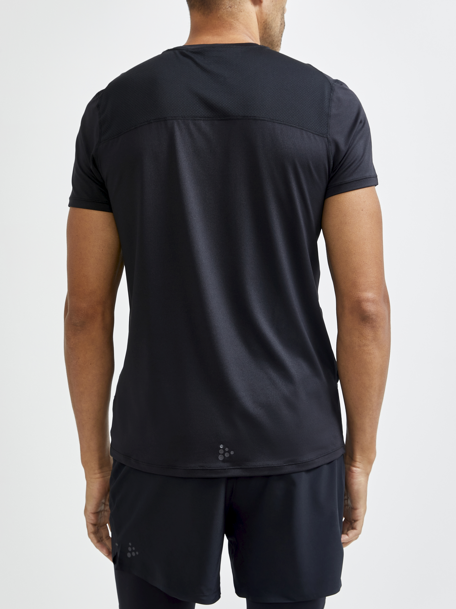 Man models black athletic t-shirt with breathable mesh panel on back.