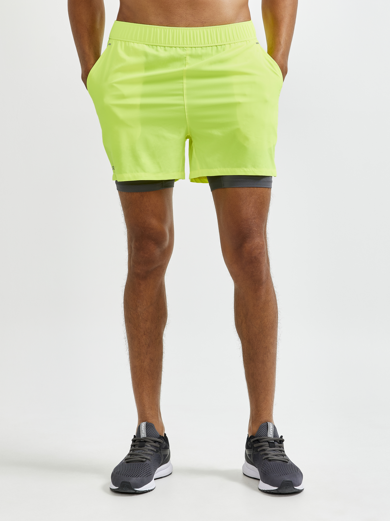 Man models neon yellow running shorts with built-in liner shorts.