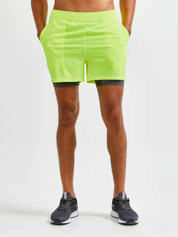 Man models neon yellow running shorts with built-in liner shorts.