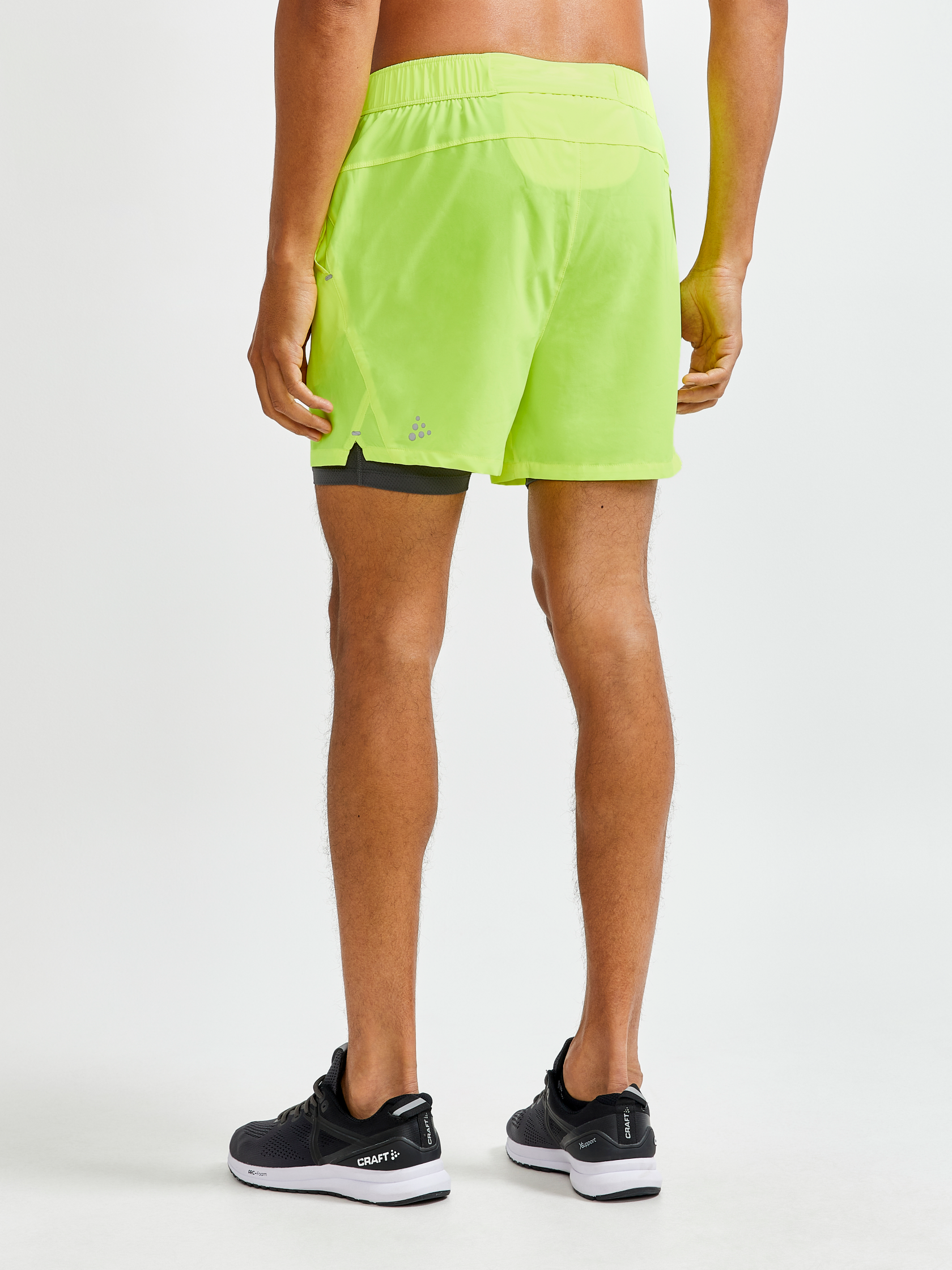 Man models neon yellow running shorts with built-in liner from the back.