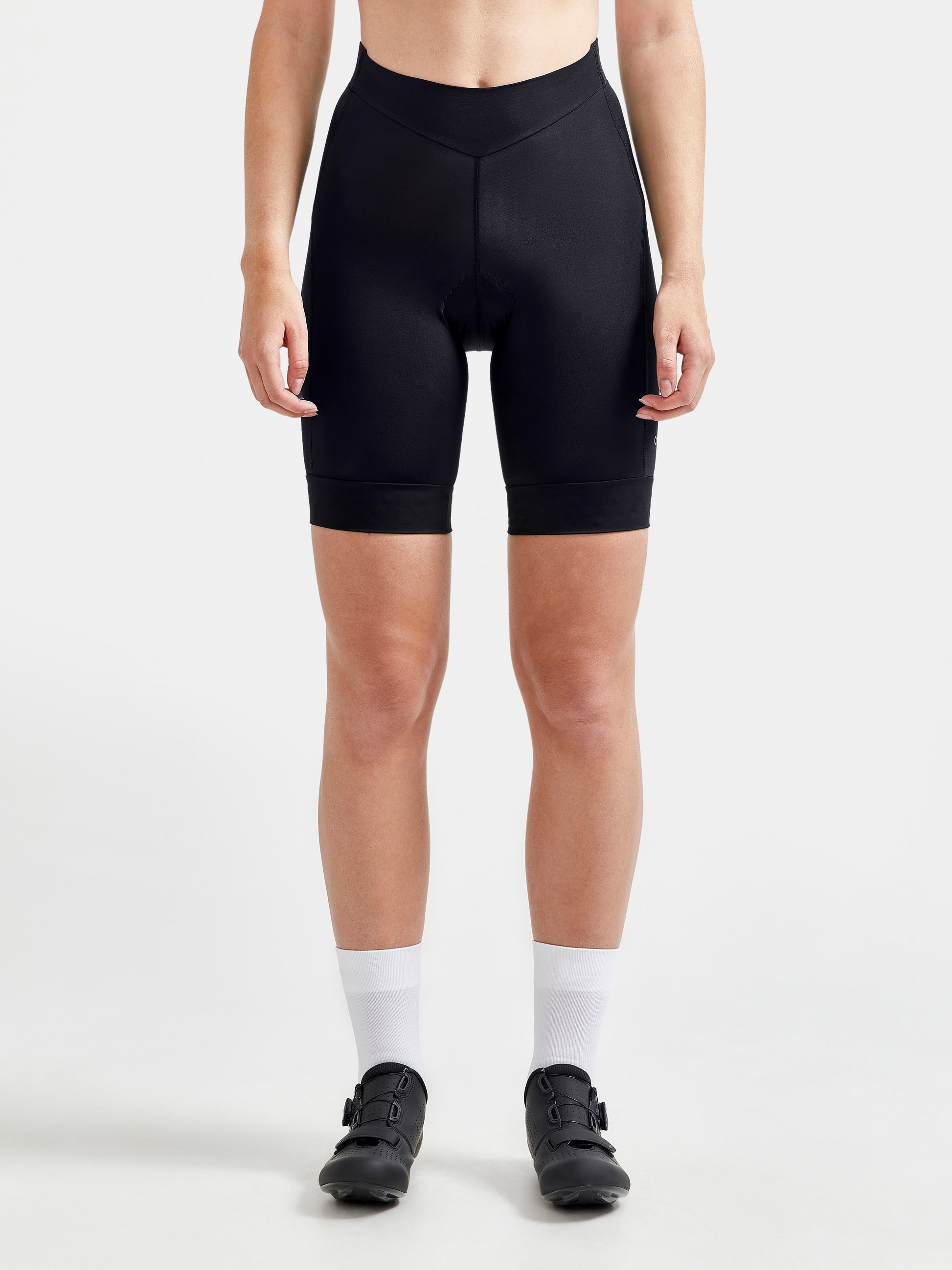 Woman models black cycling shorts with white background.
