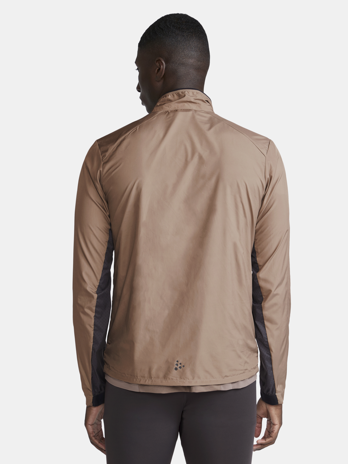 Man models a lightweight, tan men's running jacket with black accents, showcasing the back view.