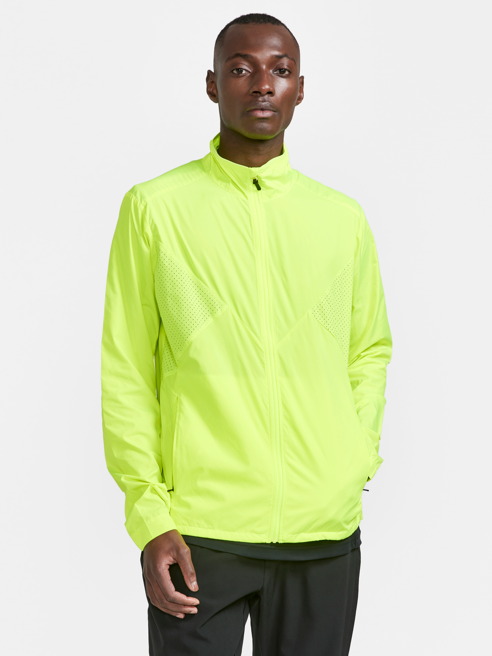 Man wears a neon yellow lightweight running jacket with zippered pockets.