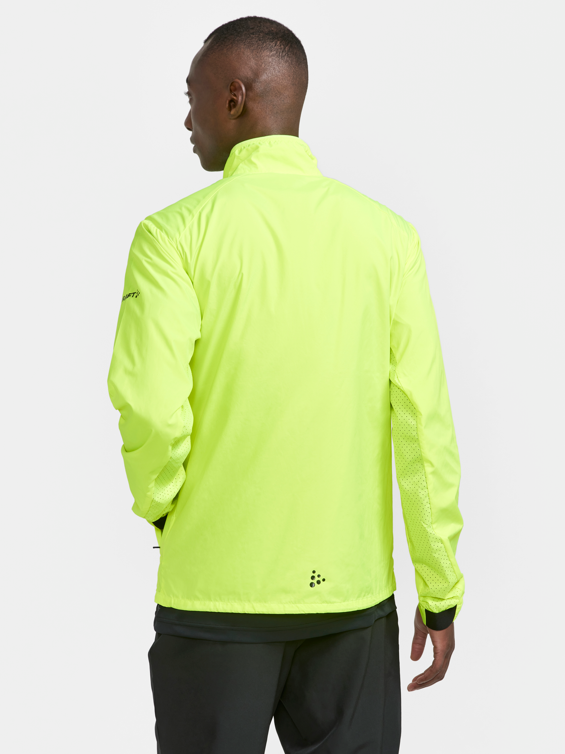 Man models a neon yellow running jacket with ventilated panels on the sides, highlighting its breathability for active wear.