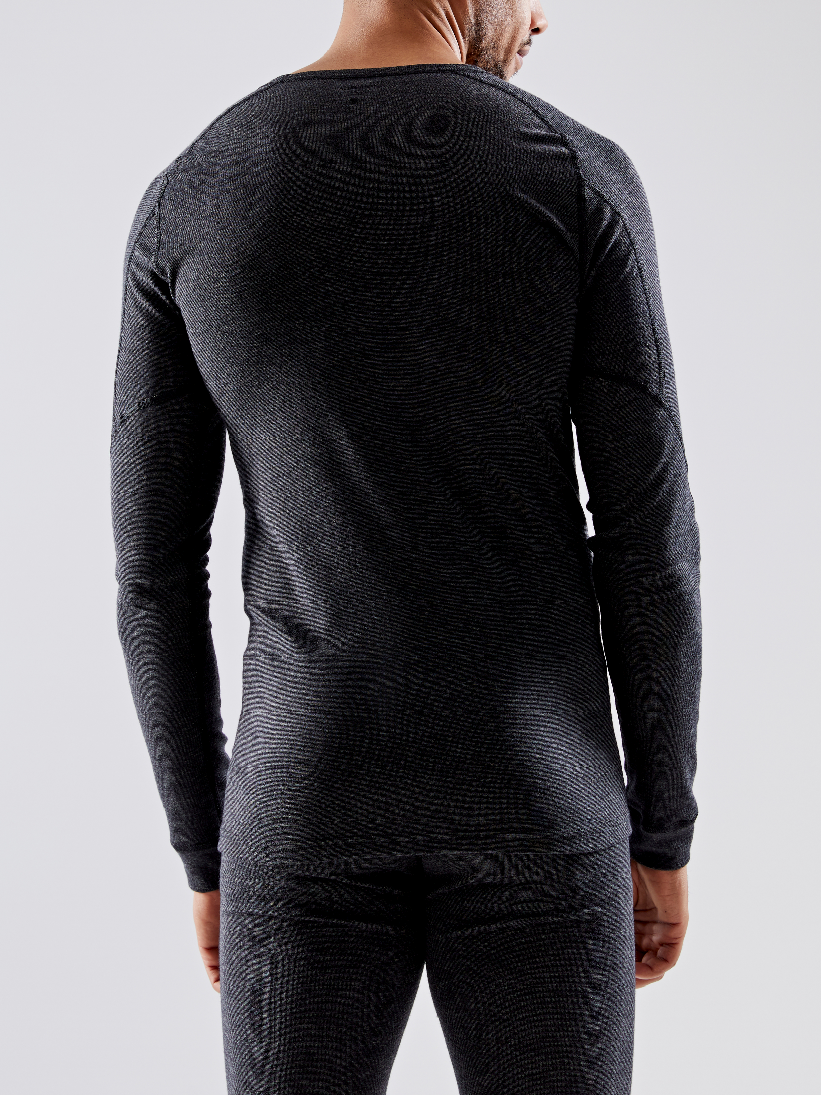 Man models a charcoal grey, long-sleeved thermal shirt and leggings.