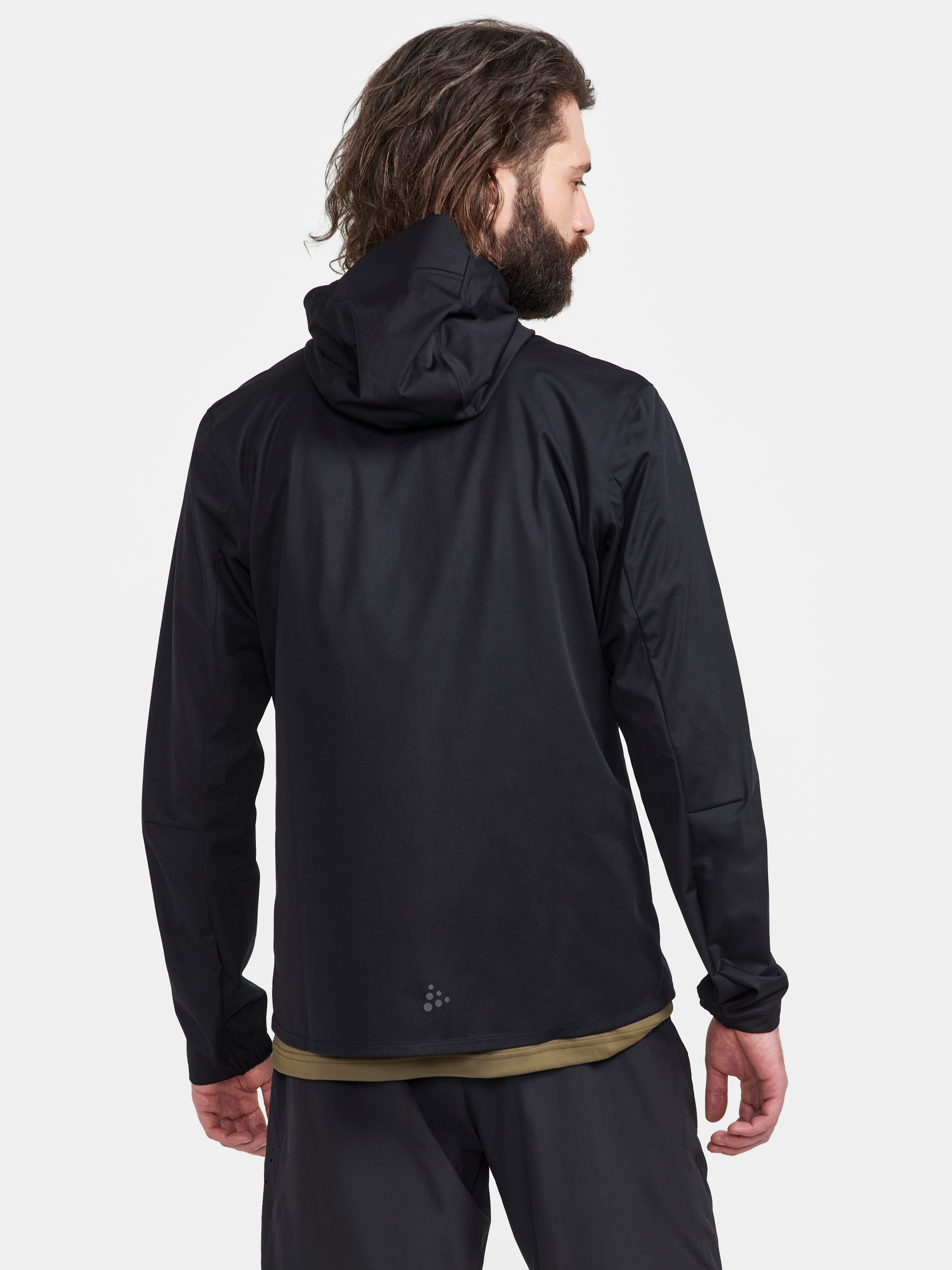 Man models a black hooded weatherproof jacket from the back.
