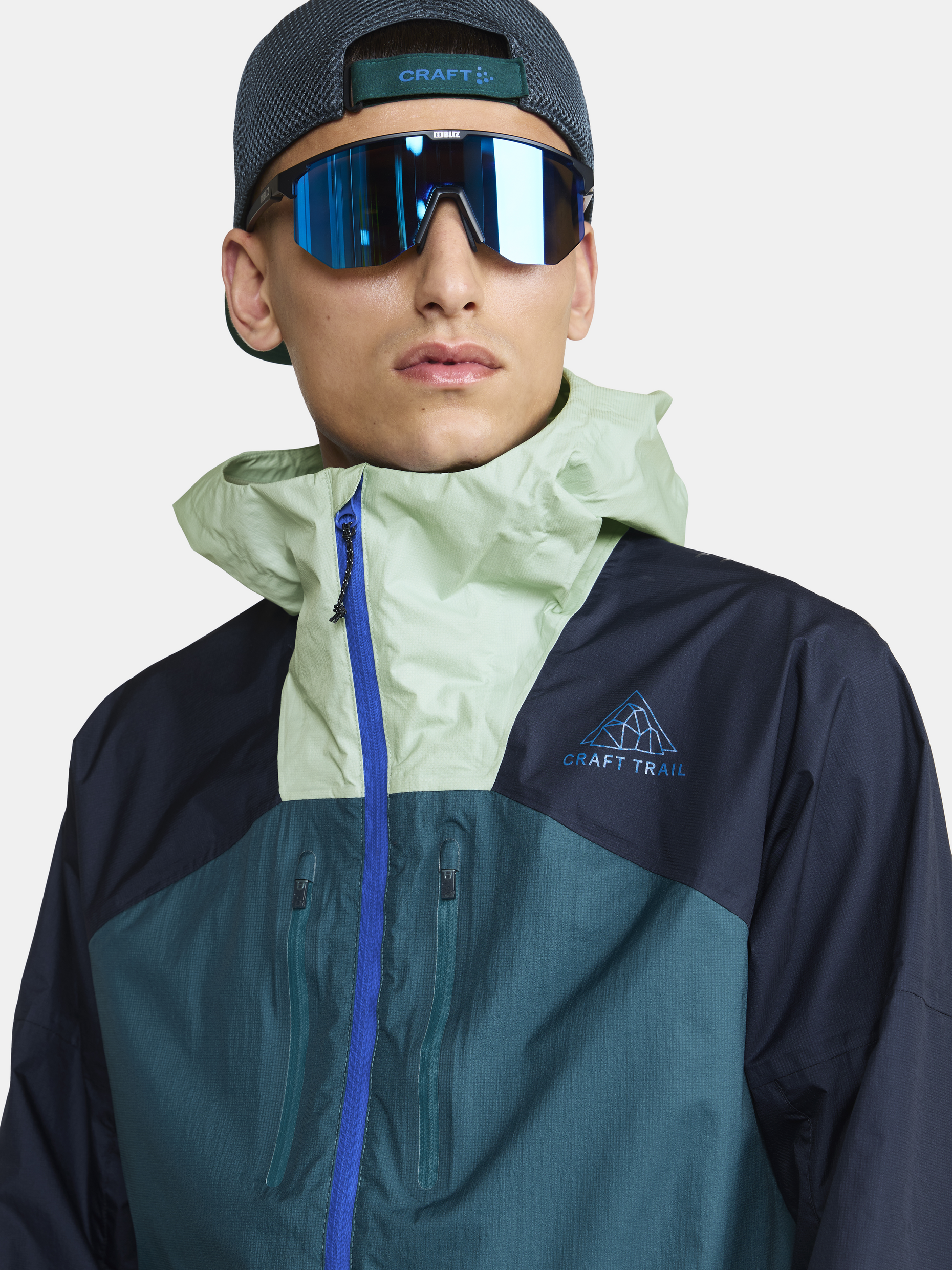 Man wearing a green and blue Craft Trail jacket with a hood.