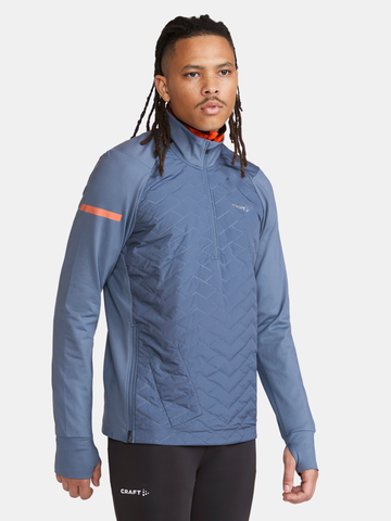 Man models a blue Craft® athletic quarter-zip pullover with chevron quilting and orange accents.