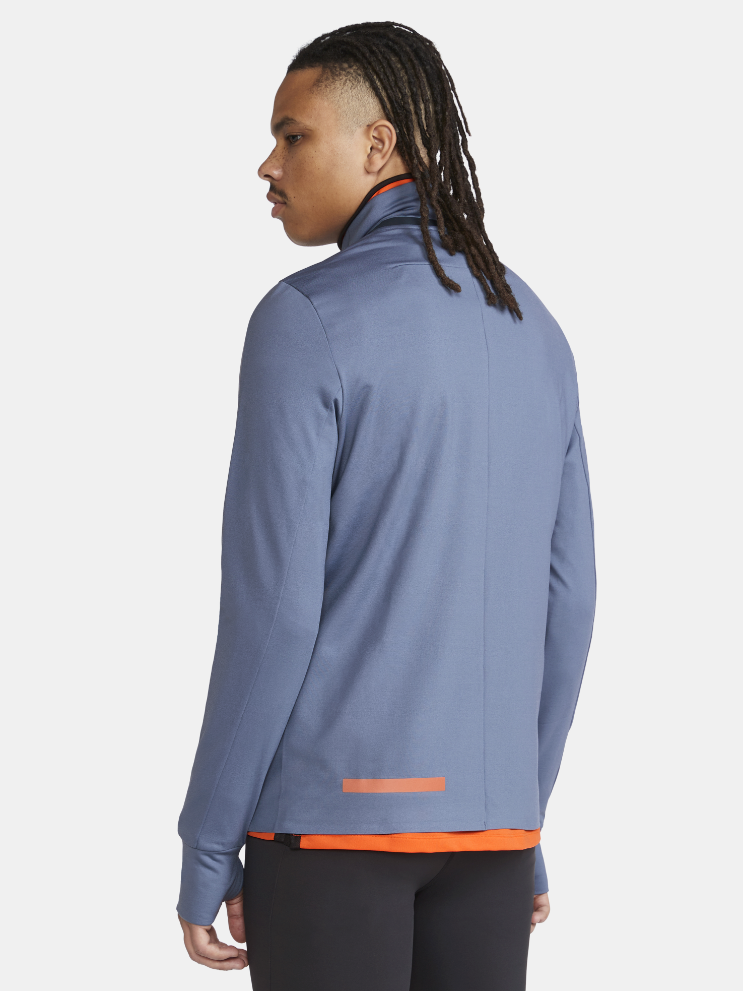 Man models a slate blue athletic jacket with a high collar and orange accent stripe across the back.