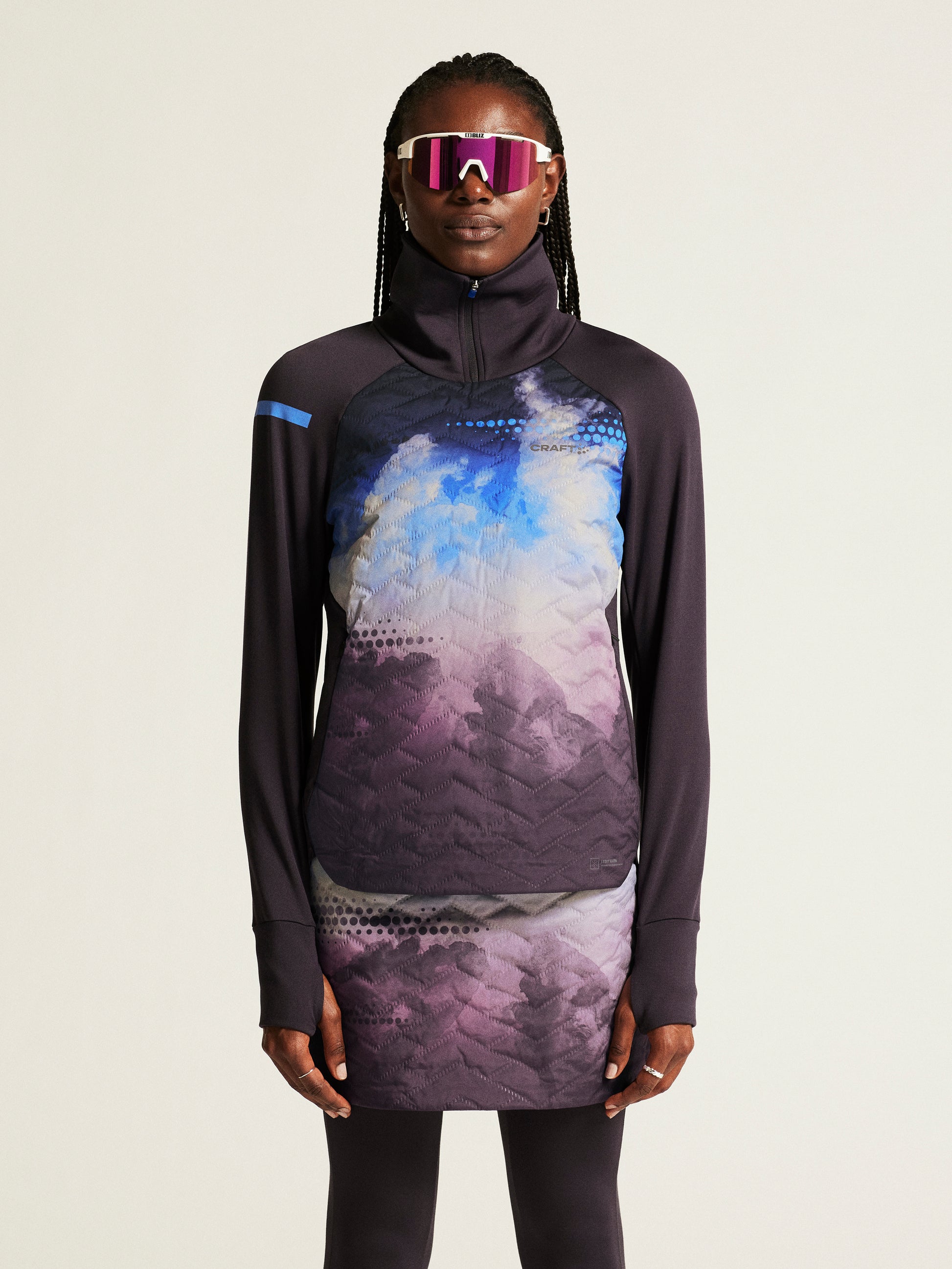 Woman models a black athletic running top and skort with a blue and purple abstract mountain print.