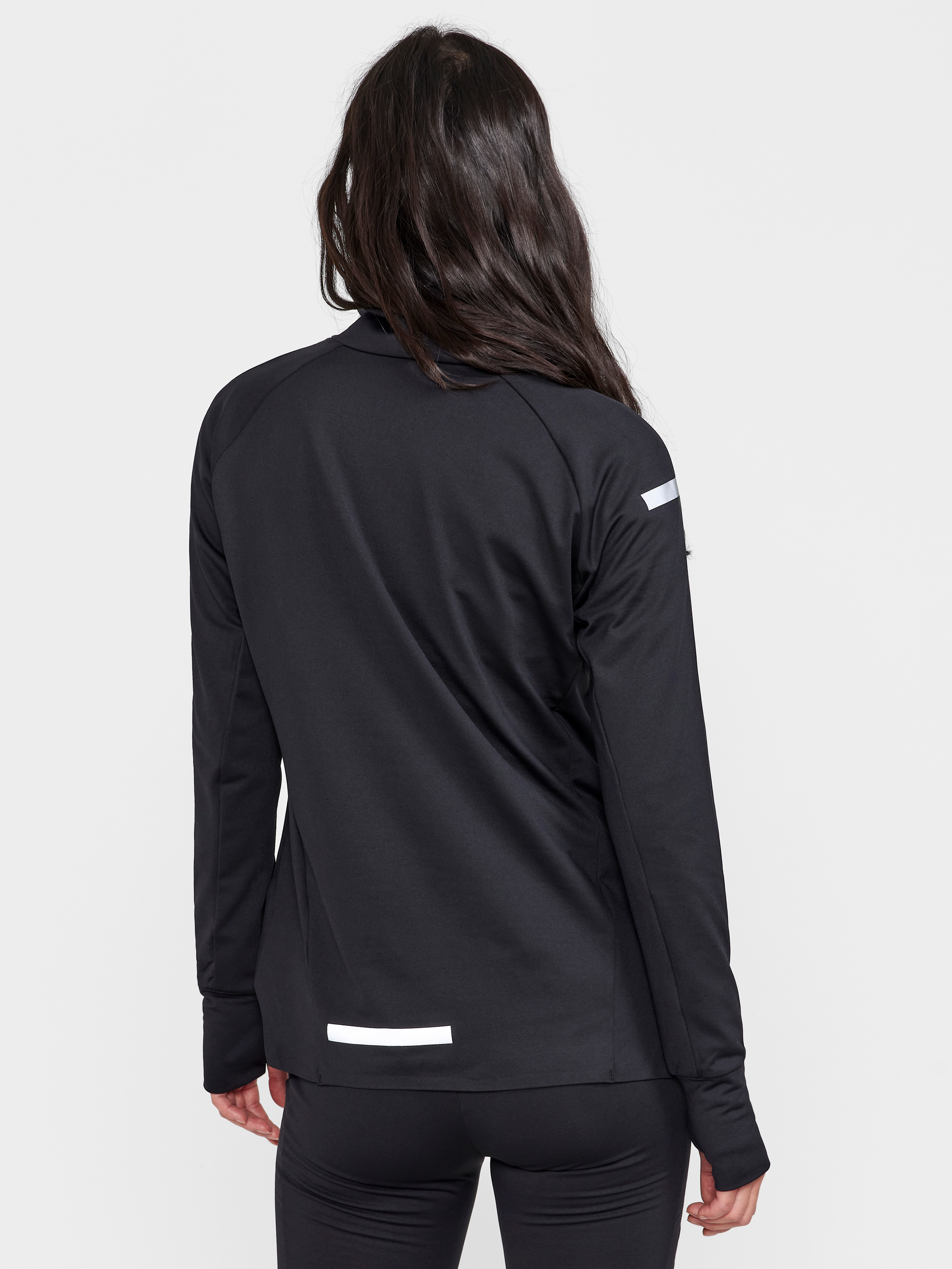 Woman models black athletic jacket with reflective details from the back.