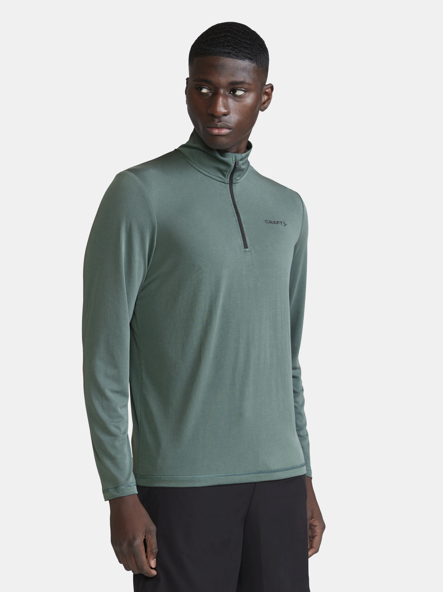 Man models a green long-sleeve athletic shirt with a quarter-zip.