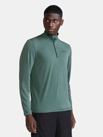 Man models a green long-sleeve athletic shirt with a quarter-zip.