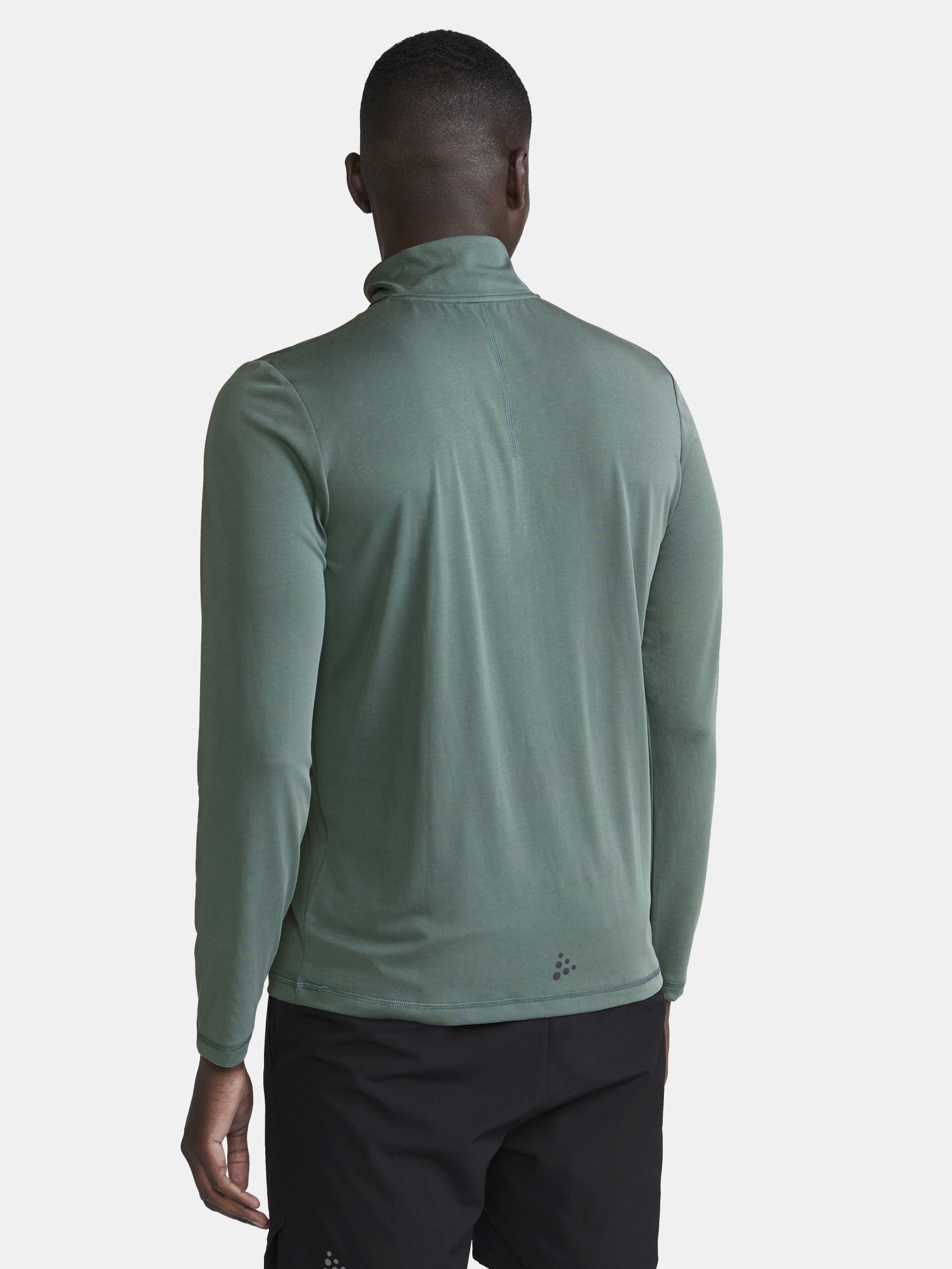 Man models green long sleeve athletic shirt from the back.