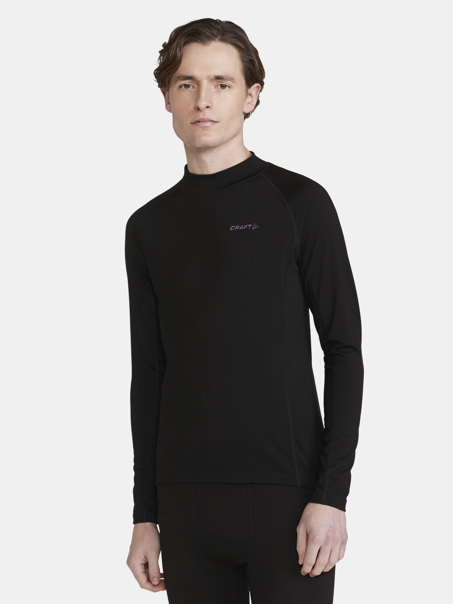 Man models a black long-sleeve base layer top with a mock neck collar.