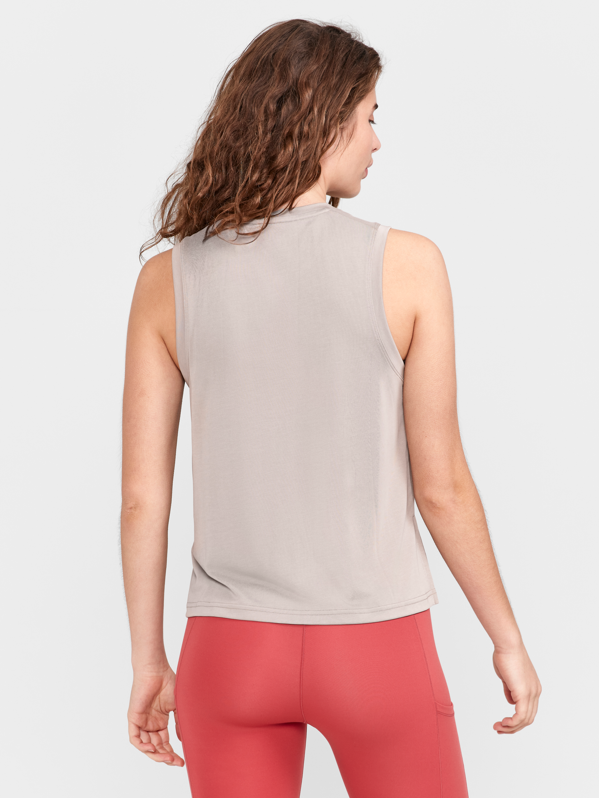 Woman models a light gray muscle tank from the back, showcasing the fit and style.