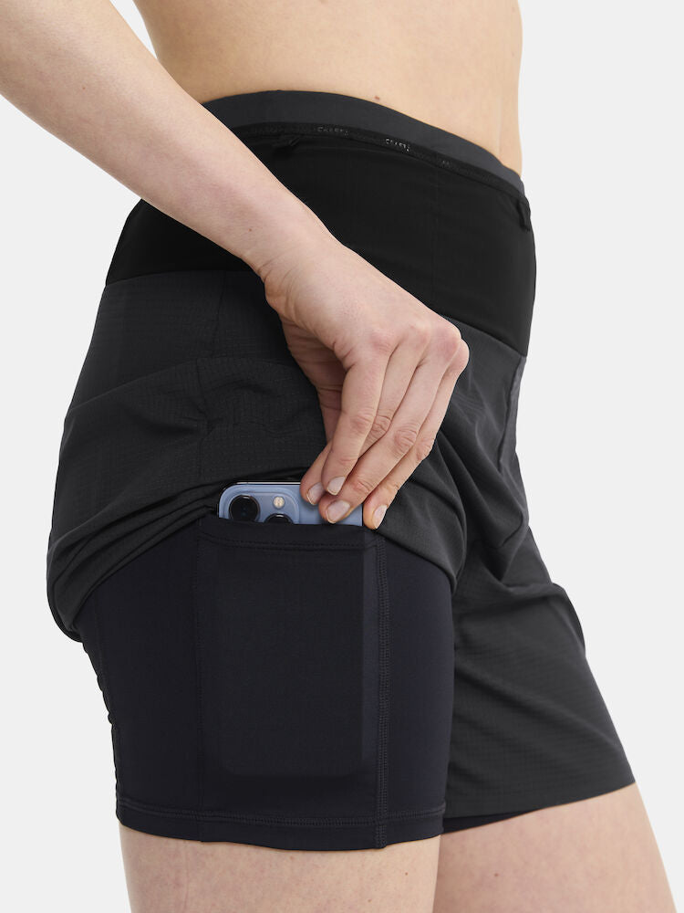 Woman placing smartphone into secure back pocket of black athletic skort.