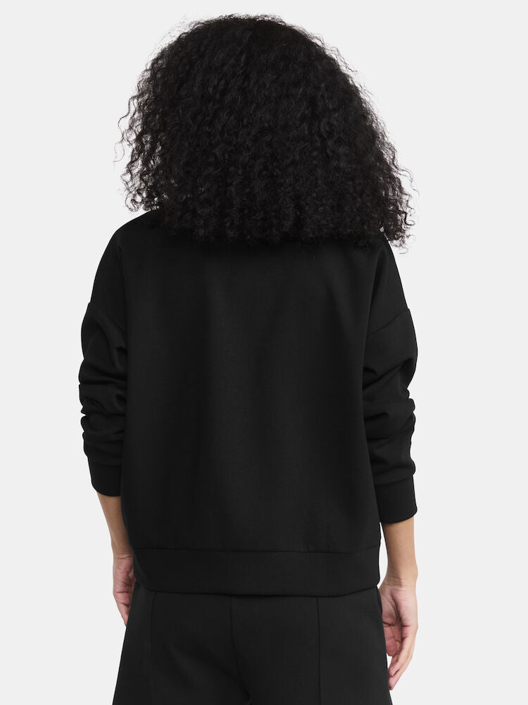 Woman models a black crewneck sweatshirt, showcasing the back view.