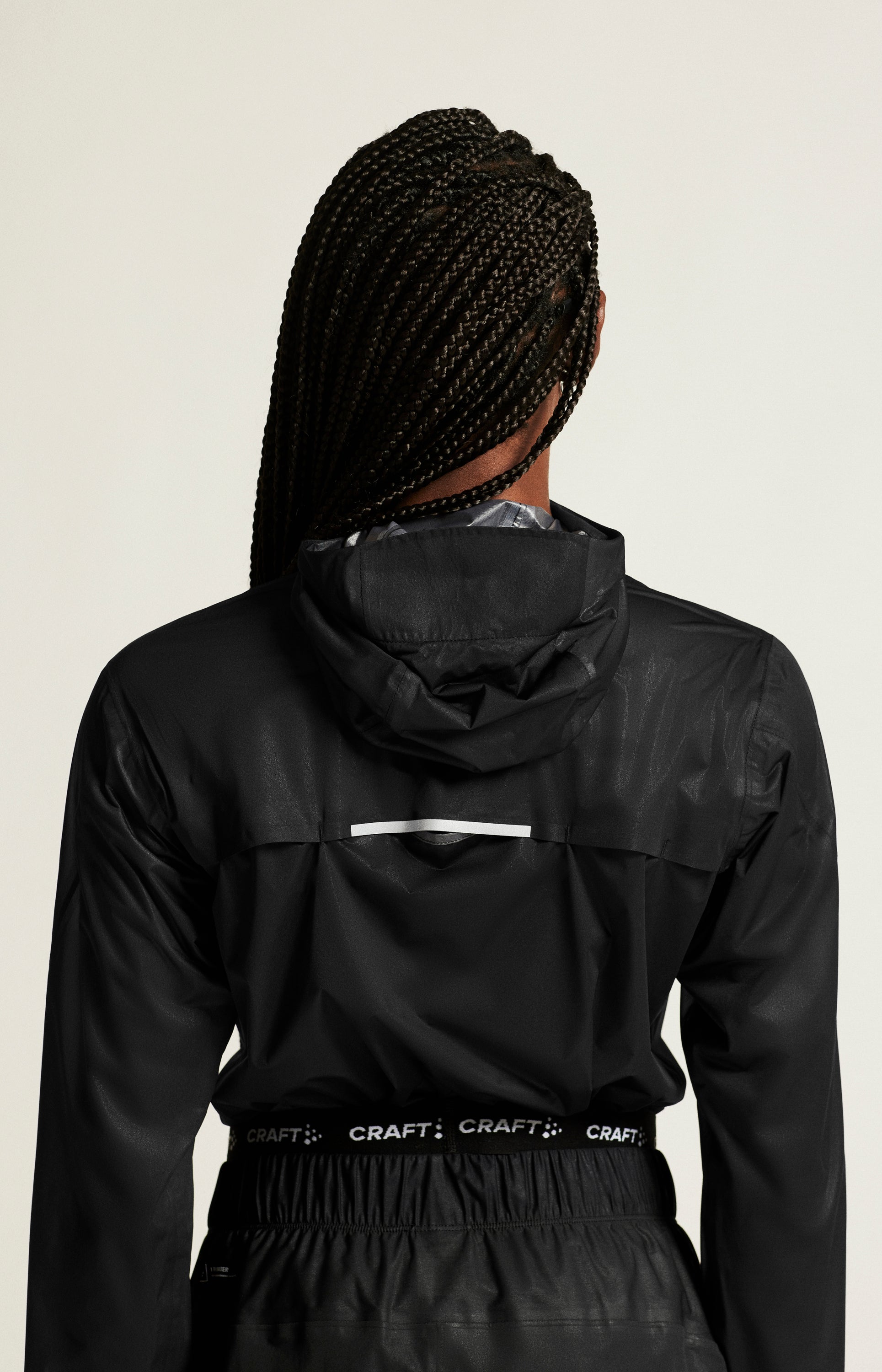 Woman modeling a black waterproof running jacket from the back.