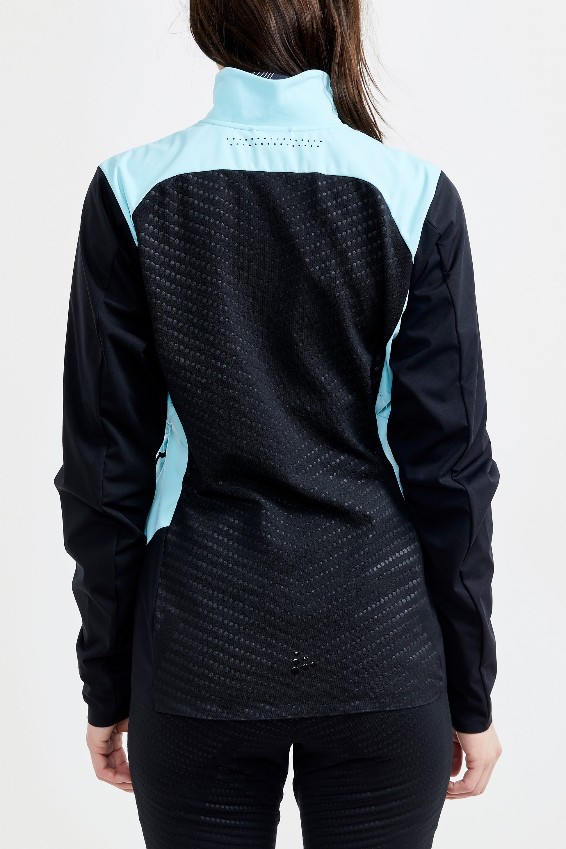 Woman models a black athletic jacket with light blue accents, showcasing the back ventilation and fitted design.
