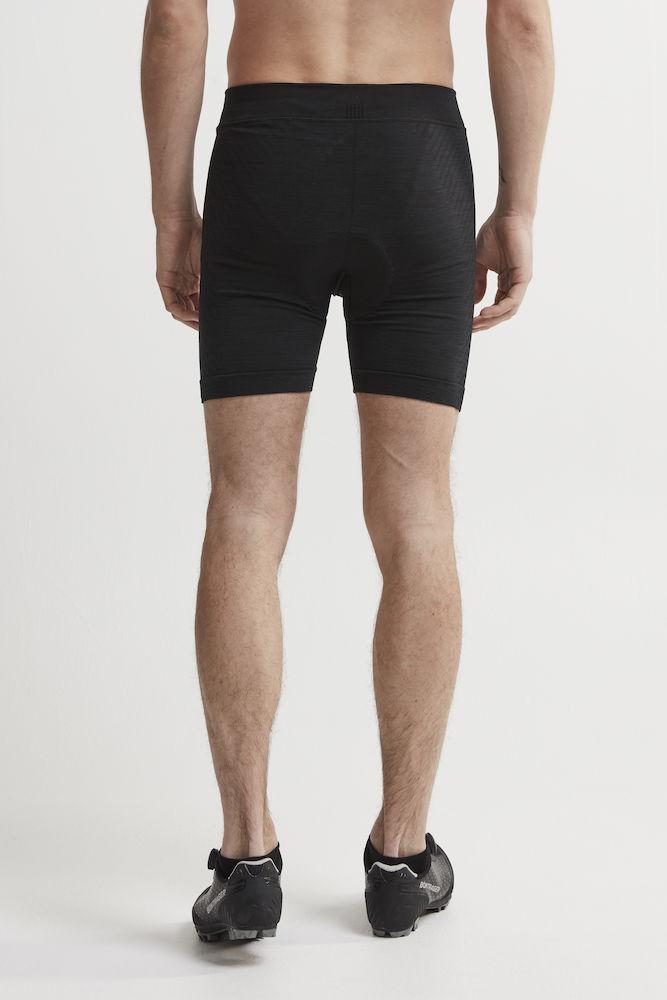 Man models black athletic base layer shorts from the back.