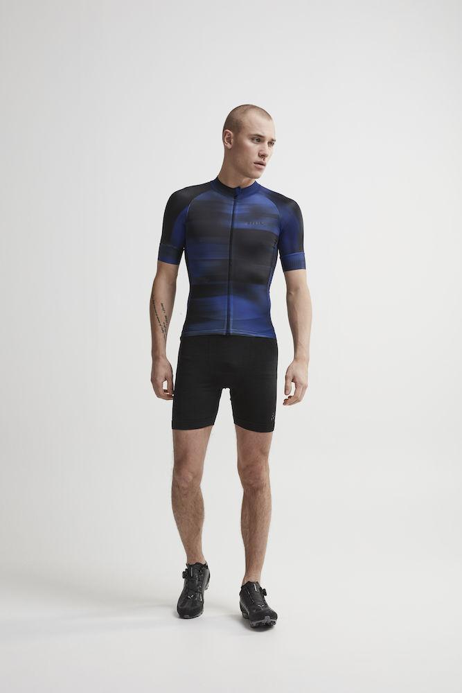 Man models a men's blue and black cycling jersey and black cycling shorts.