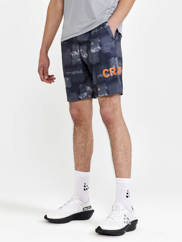 Man models gray abstract-patterned athletic shorts with orange "Craft" logo on the right leg.