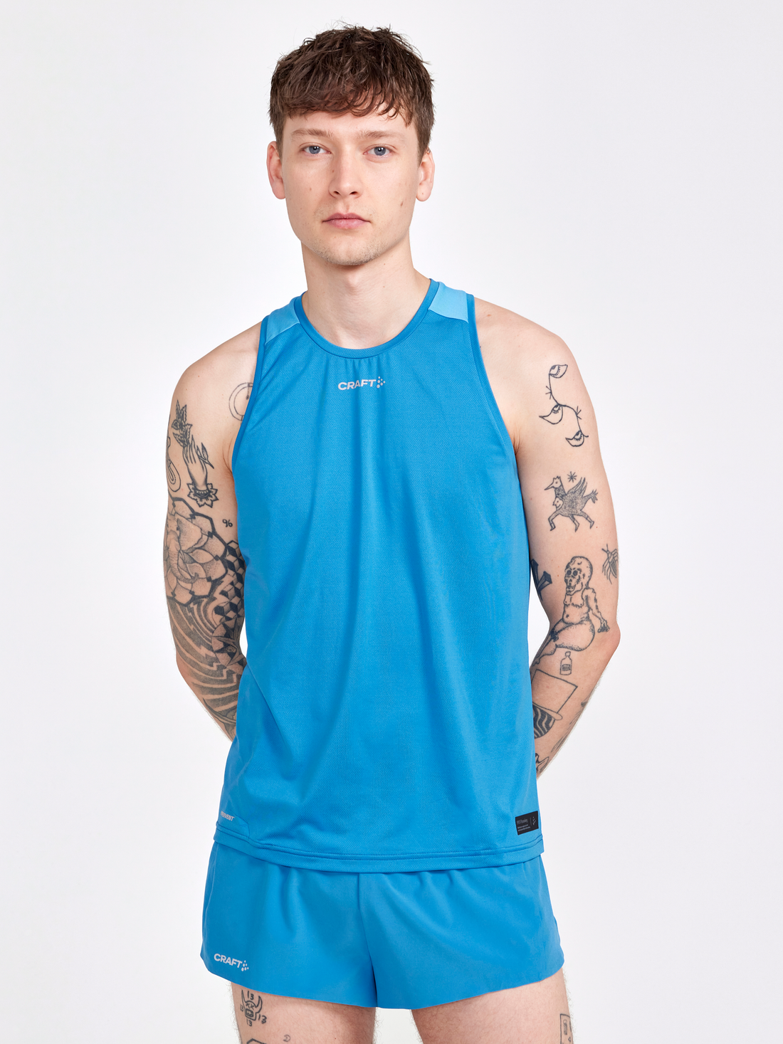 Man models a bright blue men's running tank top and shorts.