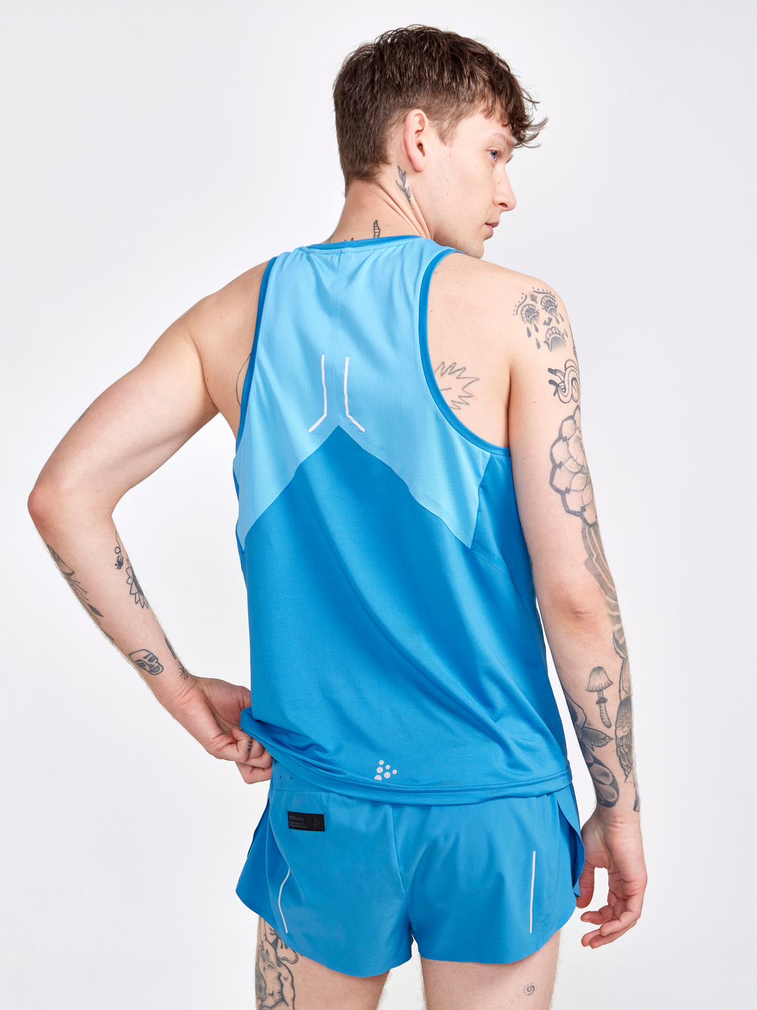 Man models a bright blue men's running tank top and shorts.