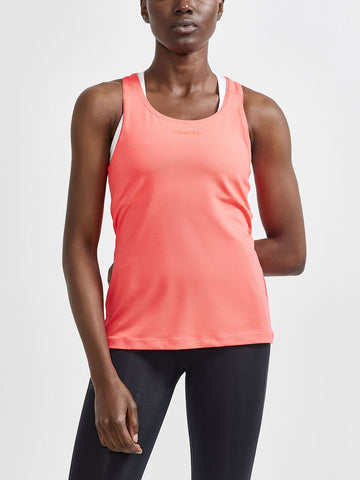 Woman models a coral pink Craft® athletic tank top and black running tights. 
