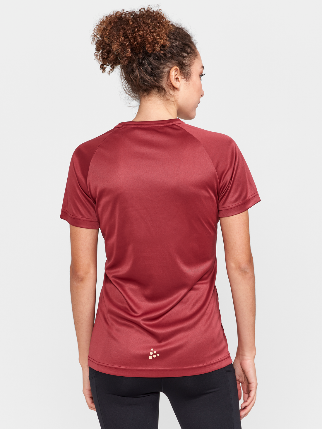 Woman models a maroon athletic t-shirt with the Craft logo on the chest. 
