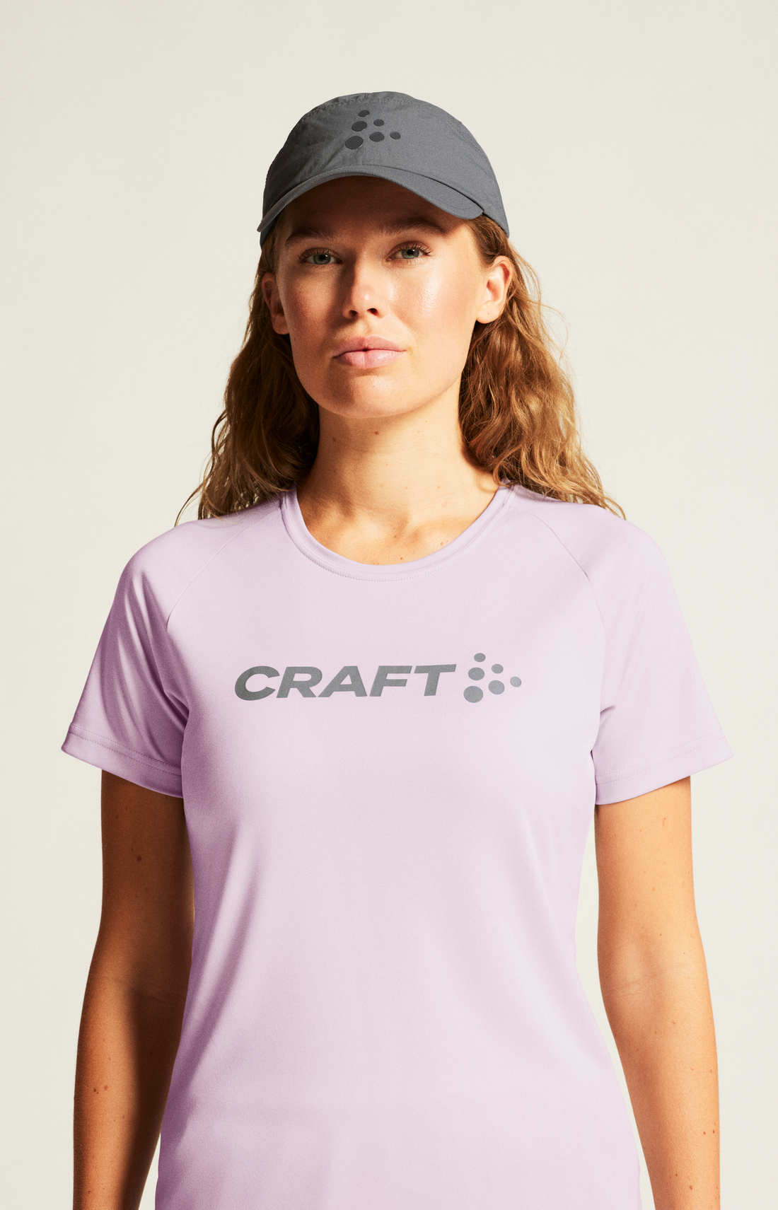 Woman wears a lavender Craft Sportswear t-shirt and a gray Craft cap. 
