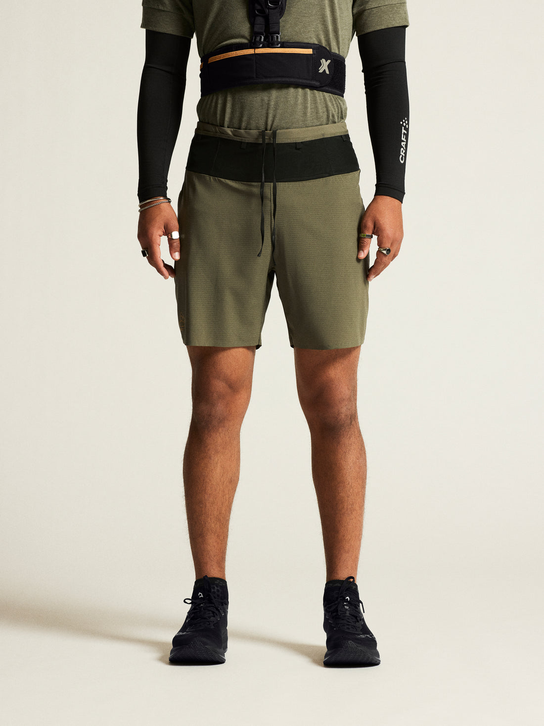 Man models olive green running shorts and black compression sleeves. 
