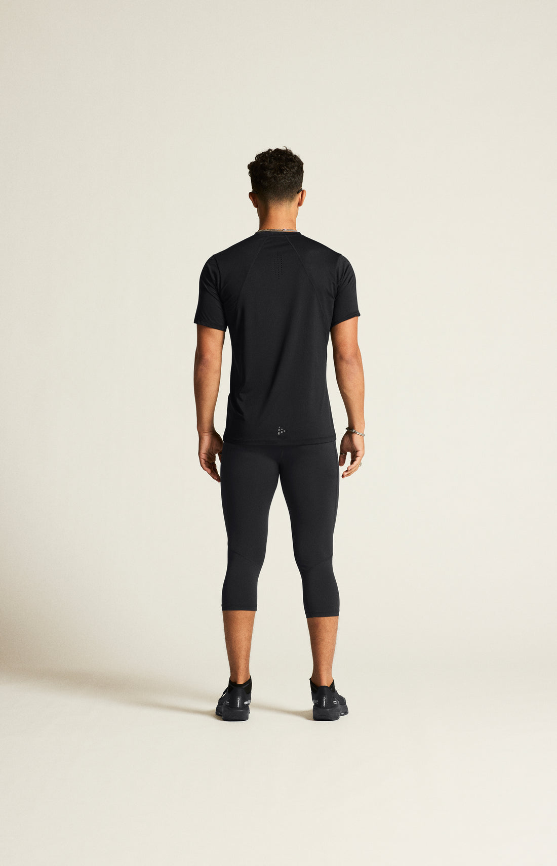 Man models a black athletic t-shirt and black running tights. 
