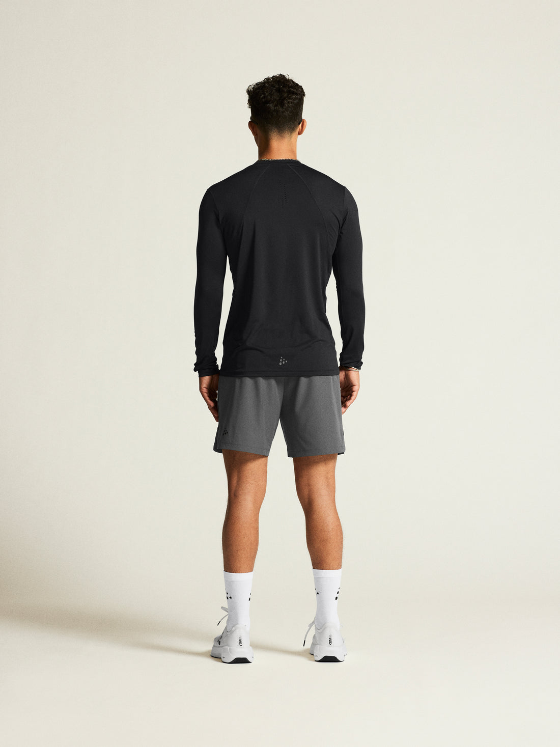 Man models a black long-sleeve athletic shirt and gray athletic shorts. 
