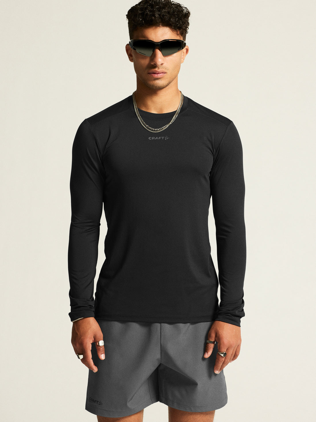 Man models a black long-sleeve athletic shirt and gray athletic shorts. 
