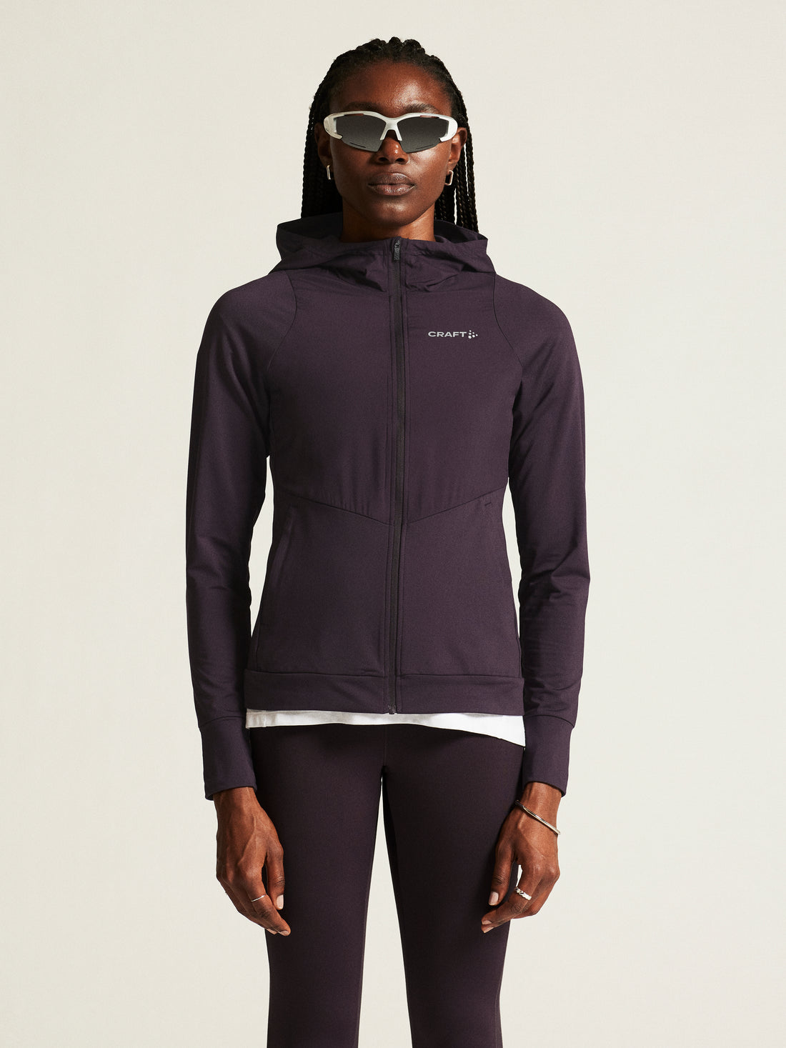 Woman models a plum-colored athletic hoodie with a full-zip front and hood. 

