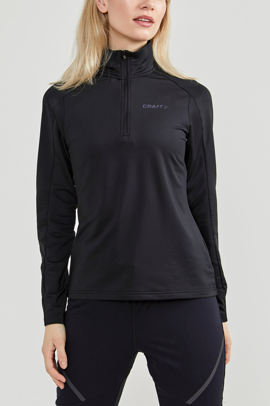 Woman models a black Craft® quarter-zip athletic top with a high collar. 

