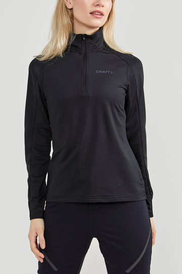 Woman models a black Craft® quarter-zip athletic top with a high collar. 
